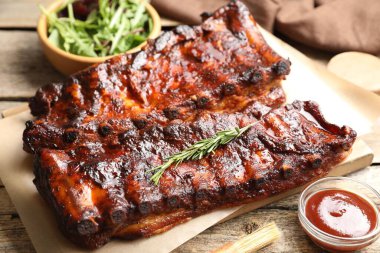 Biberiyeli, soslu ve ahşap masada salatalı domuz pirzolası.