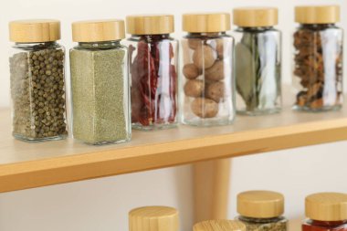Kapalı alanda, ahşap raflardaki kavanozlardaki farklı aromatik baharatlar.