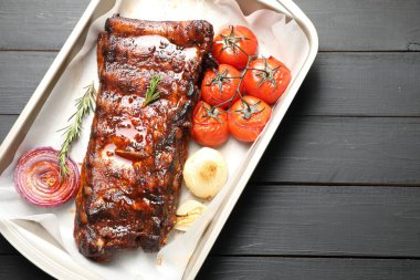 Lezzetli kaburgalar, biberiye, fırında soğan ve gri ahşap masada kurutulmuş domatesler, üst manzara. Metin için boşluk