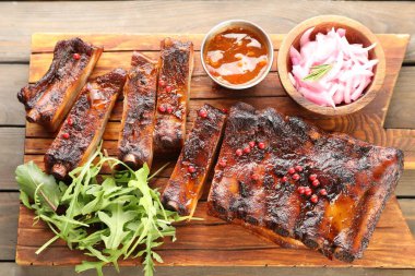 Lezzetli domuz pirzolası, roka, sos ve soğan ahşap masa, üst manzara.