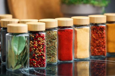 Ayna yüzeyindeki kavanozlarda farklı aromatik baharatlar, yakın plan.