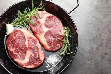 Çiğ et ve baharat parçaları gri desenli masa üzerinde fırın kabında, üst manzara. Metin için boşluk