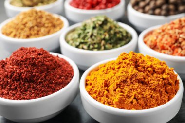 Gri masada farklı aromatik baharatlar, yakın plan.