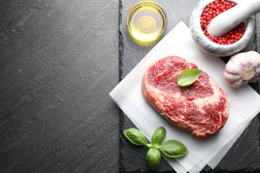 Bir parça çiğ et ve baharat siyah masada, düz yerde. Metin için boşluk