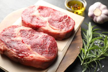 Çiğ et parçaları ve baharatlar siyah masada, yakın plan.