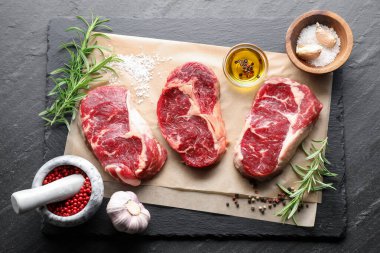 Çiğ et parçaları ve baharatlar siyah masanın üzerinde, düz yatıyordu.