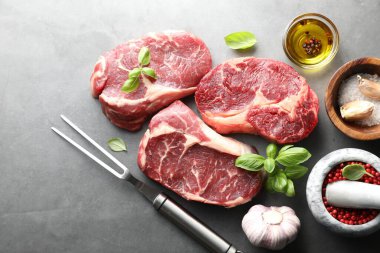 Çiğ et, baharat ve çatal parçaları gri masada, düz yatıyordu.