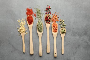 Gri masadaki kaşıklardaki farklı baharatlar düzdü.