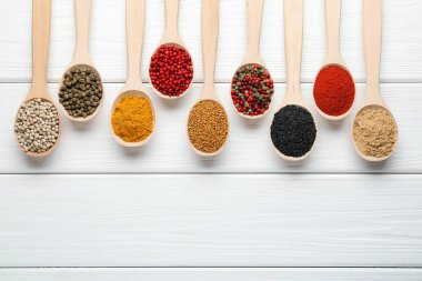 Beyaz ahşap masadaki kaşıklardaki farklı aromatik baharatlar. Metin için boşluk