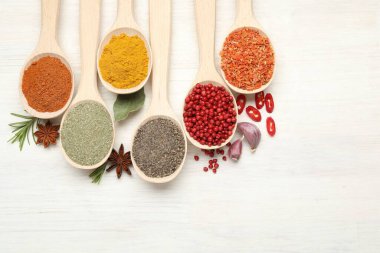 Beyaz ahşap masadaki kaşıklardaki farklı aromatik baharatlar.