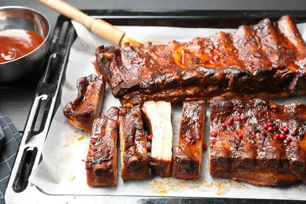 Lezzetli kaburgalar, sos ve fırça gri masada, yakın plan.