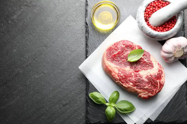 Bir parça çiğ et ve baharat siyah masada, düz yerde. Metin için boşluk