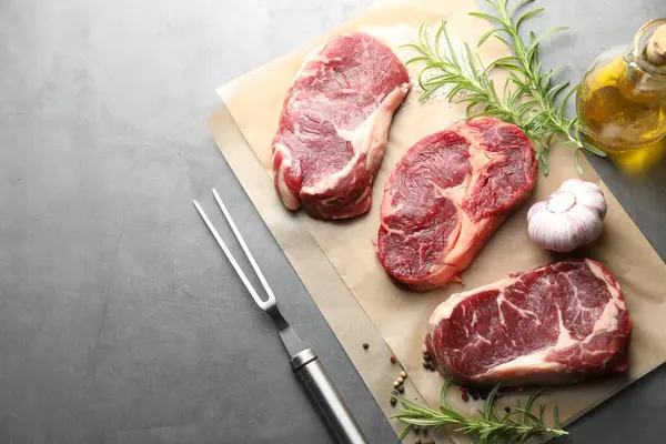 Çiğ et, baharat ve çatal parçaları gri masada, düz yerde. Metin için boşluk