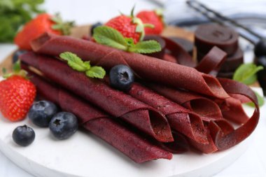 Lezzetli meyve dürümleri, çilekler, yaban mersini ve nane şekeri beyaz masada, yakın plan.