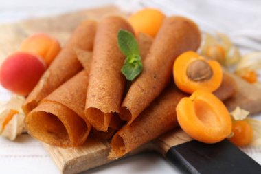 Lezzetli meyve dürümleri, kayısılar ve beyaz ahşap masa üzerinde bitki salatası, yakın plan.