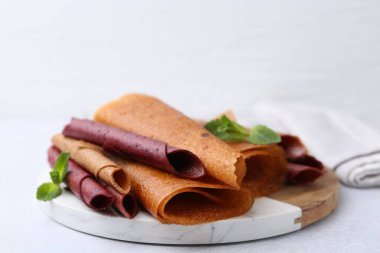 Lezzetli meyve ruloları ve nane şekeri ışık masasında, yakın plan.