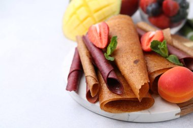 Lezzetli meyve dürümleri, nane, mango ve böğürtlenler ışık masasında, yakın plan. Metin için boşluk