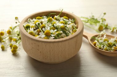 Taze papatya çiçekleri kâsede ve kaşık açık tahta masada, yakın plan.