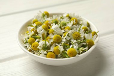 Taze papatya çiçekleri kasede beyaz ahşap masada, yakın plan.