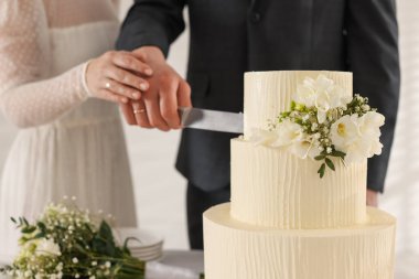 Yeni evliler içeride düğün pastasını kesiyorlar. Seçici bir odak noktası.