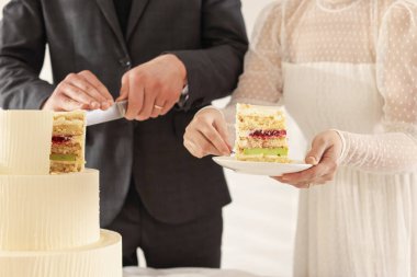 Yeni evliler arka planda düğün pastası kesiyorlar, yakın plan.