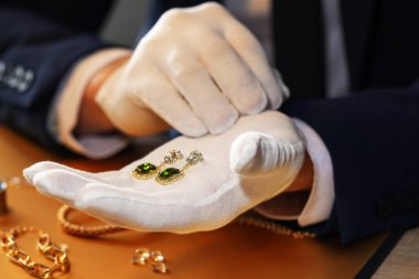 Masada lüks küpelerle çalışan eksper, yakın plan.