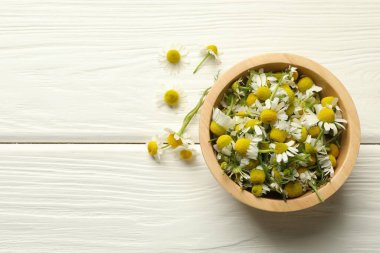 Taze papatya çiçekleri ve beyaz ahşap masada bir kase, düz uzanmış. Metin için boşluk