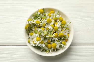Beyaz ahşap masada kasede taze papatya çiçekleri.