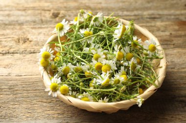 Taze papatya çiçekleri hasır sepetin içinde ahşap masanın üzerinde, yakın plan.