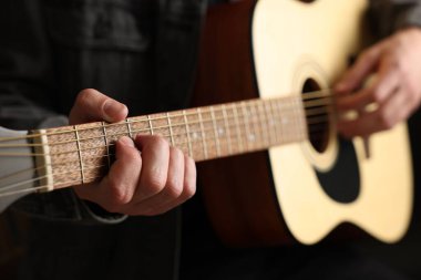 Siyah arkaplanda gitar çalan adam, yakın plan