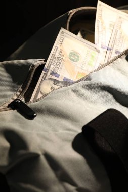 Siyah arkaplanda dolar banknotları olan çanta, yakın plan.