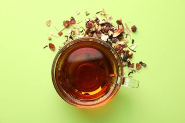 Cam fincanda nefis bitki çayı ve açık yeşil arka planda kuru yapraklar.