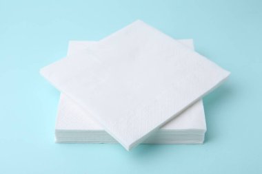 Açık mavi arkaplanda tek kullanımlık kağıt mendil yığını, yakın plan