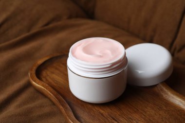 Kahverengi kanepede vücut kremi kavanozu, yakın plan.