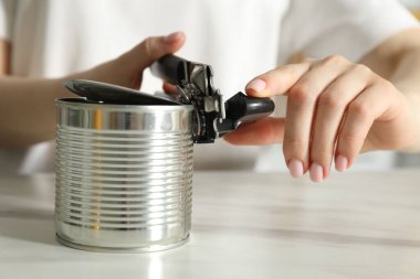 Beyaz masada konserve açacağıyla konserve açan kadın, yakın çekim
