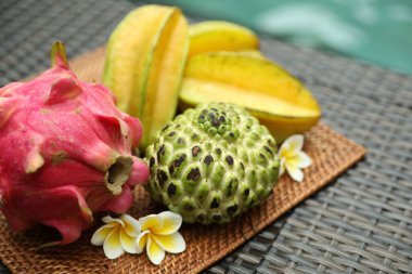 Yüzme havuzu yakınındaki hasır masada farklı bir tropikal meyve.