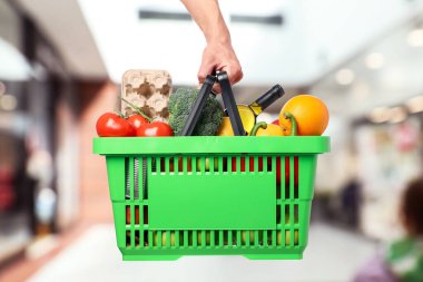 Süpermarkette elinde farklı gıda ürünleri olan bir adam var.