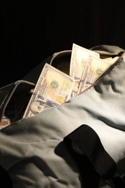 Siyah arkaplanda dolar banknotları olan çanta, yakın plan.