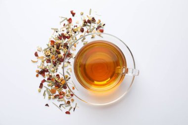 Beyaz arka planda lezzetli bitki çayı ve kuru yapraklar, üst manzara.