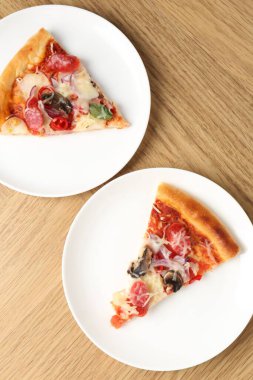 Tahta masada servis edilen ince tütsülenmiş sosisli lezzetli pizza dilimleri.