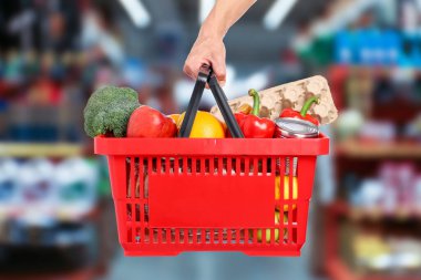 Süpermarkette elinde farklı gıda ürünleri olan bir adam var.