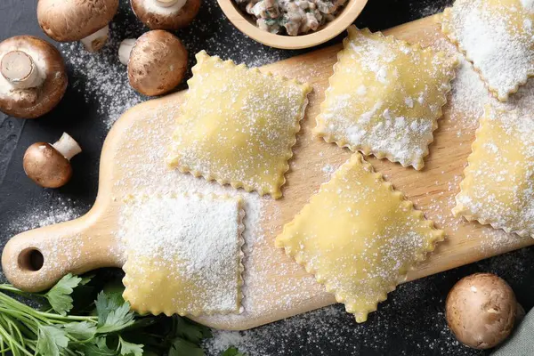 Pişmemiş ravioli ve mantarlar siyah masada, düz yatıyordu.