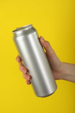 Sarı arka planda teneke kutusu olan kadın, yakın plan.