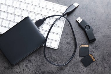 SD hafıza kartları, USB flaş bellek, kablo ve klavyeli sabit disk koyu gri tabloda düz konum