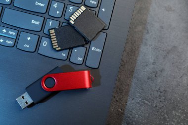 SD hafıza kartları, USB flaş bellek ve dizüstü bilgisayar koyu gri masa, üst görünüm. Metin için boşluk