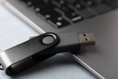 Flaş bellek ve laptop açık gri masada, yakın plan.