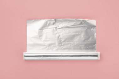 Pembe arka planda alüminyum folyo rulosu, üst görünüm