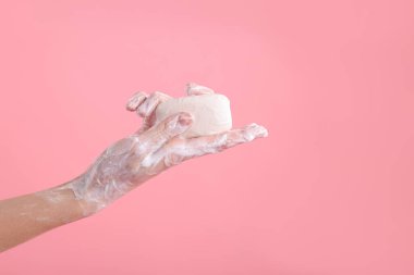 Açık pembe arka planda ellerini sabunla yıkayan kadın, yakın plan. Metin için boşluk