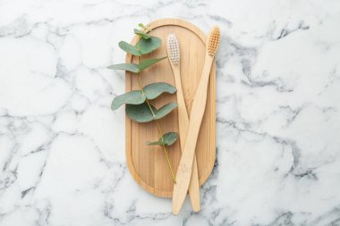 Bambu diş fırçaları ve okaliptüs dalları beyaz mermer masa, üst görünüm