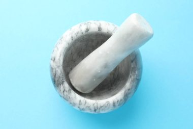 Açık mavi zemin üzerinde mermer harç ve tokmak, üst görünüm